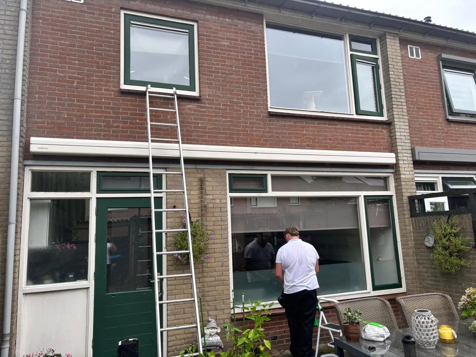 Glazenwasser aan het werk bij de achtergevel van een rijwoning