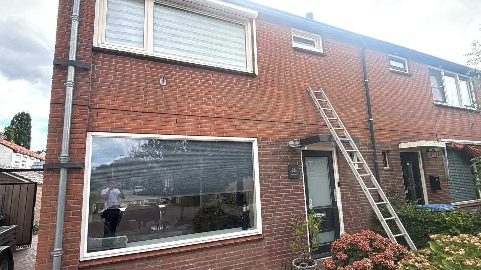 Groot raam in een voorgevel, ladder nog tegen de muur