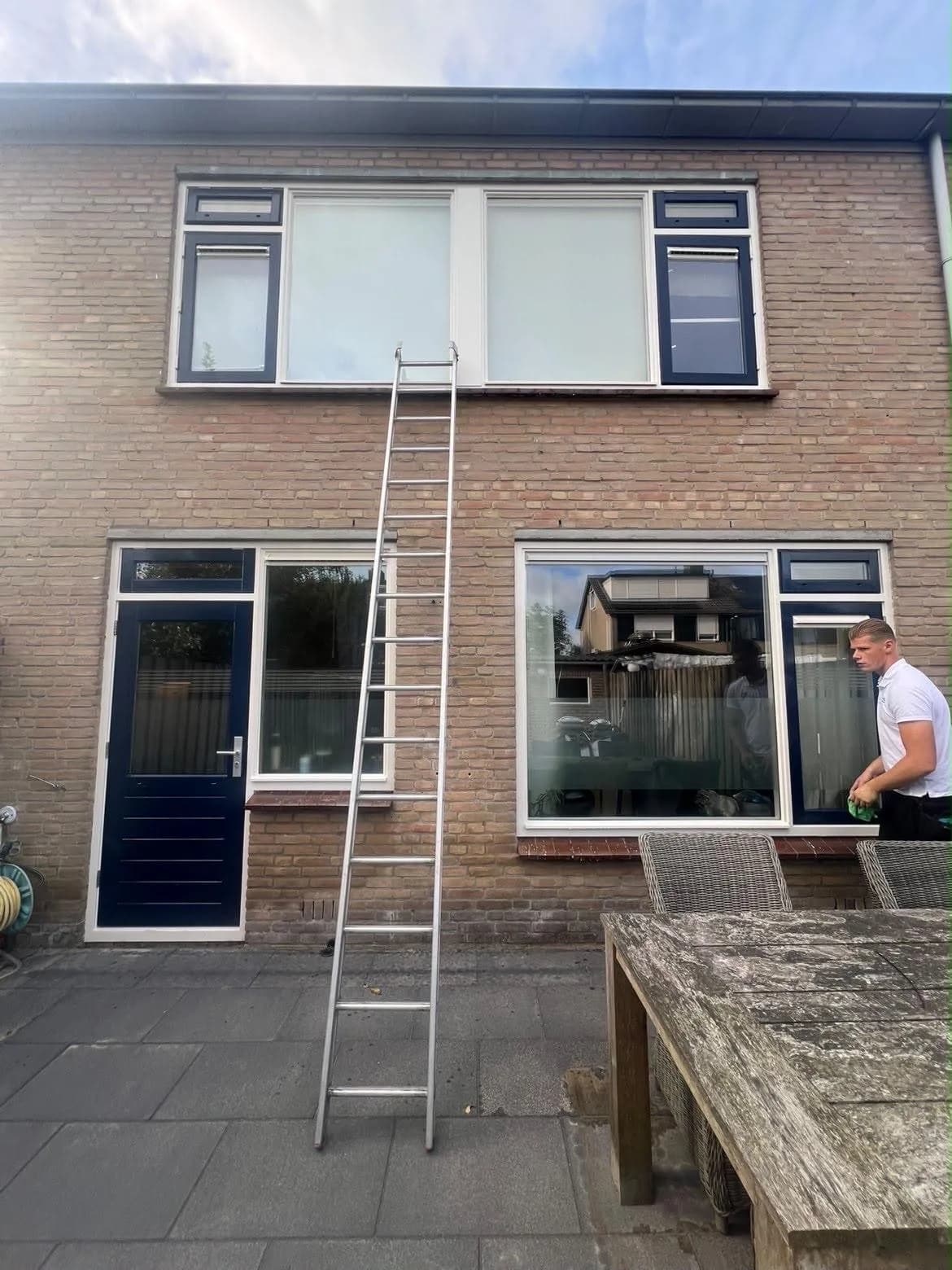 Ramen wassen aan de achterkant van een rijwoning, ladder tegen de gevel
