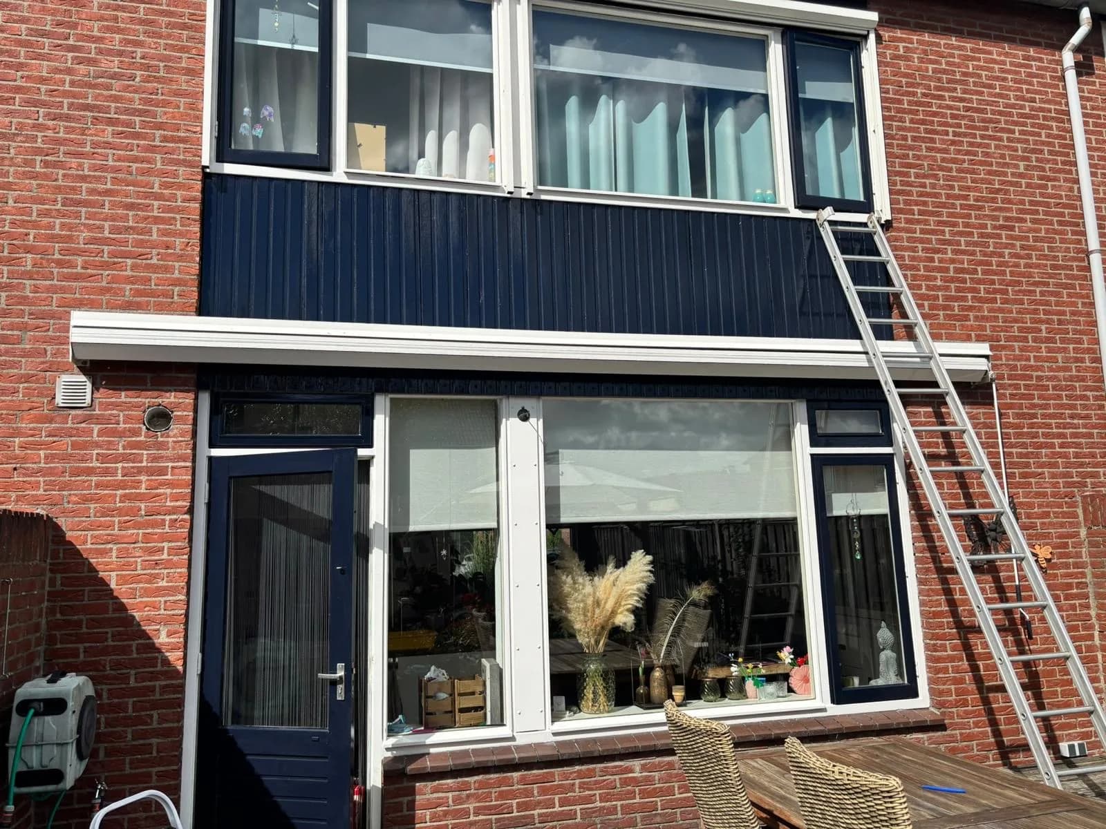 Rijwoning met ladder tegen de gevel tijdens het glazenwassen