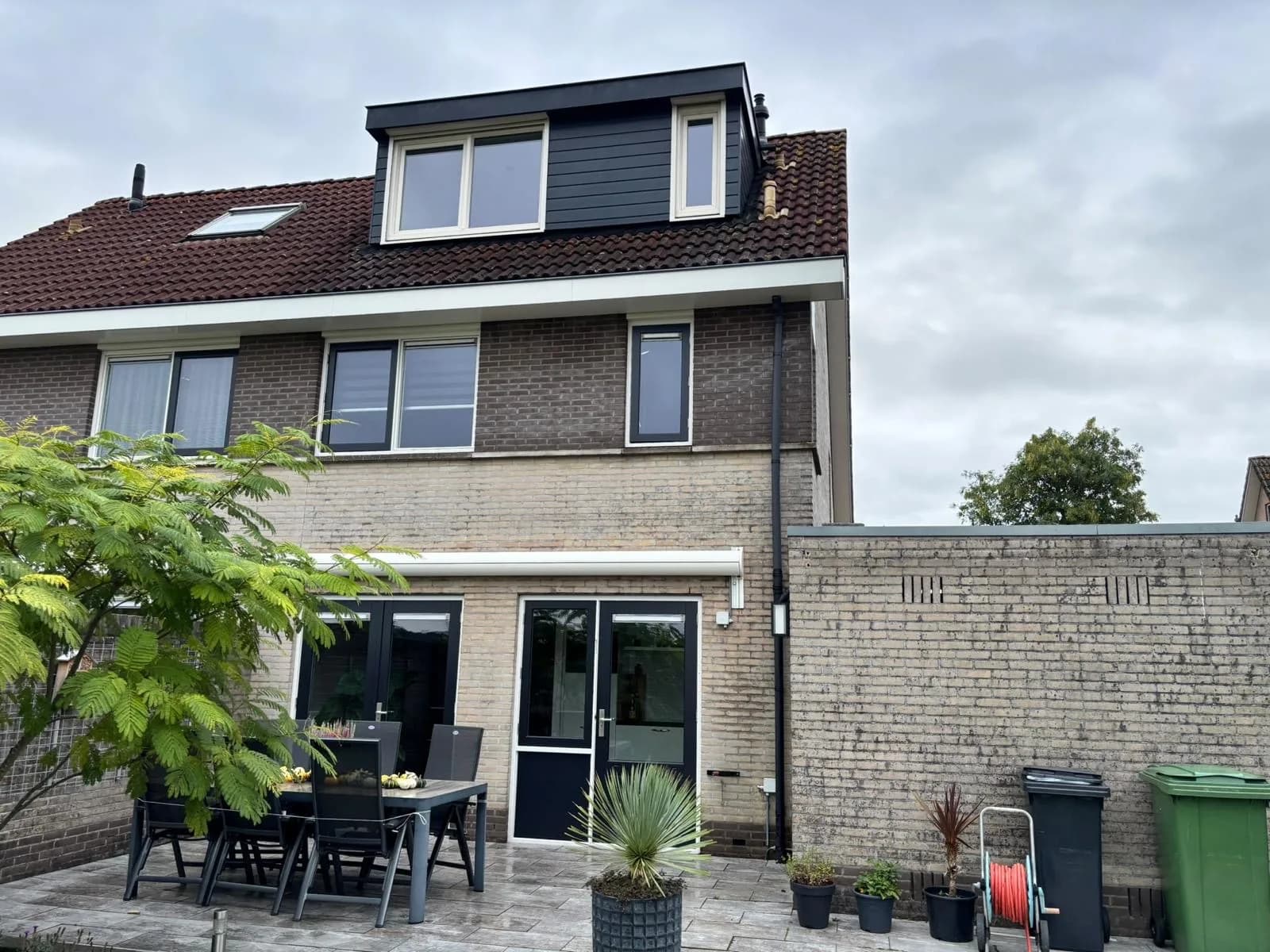 Achterkant van een woning met dakkapel en tuin
