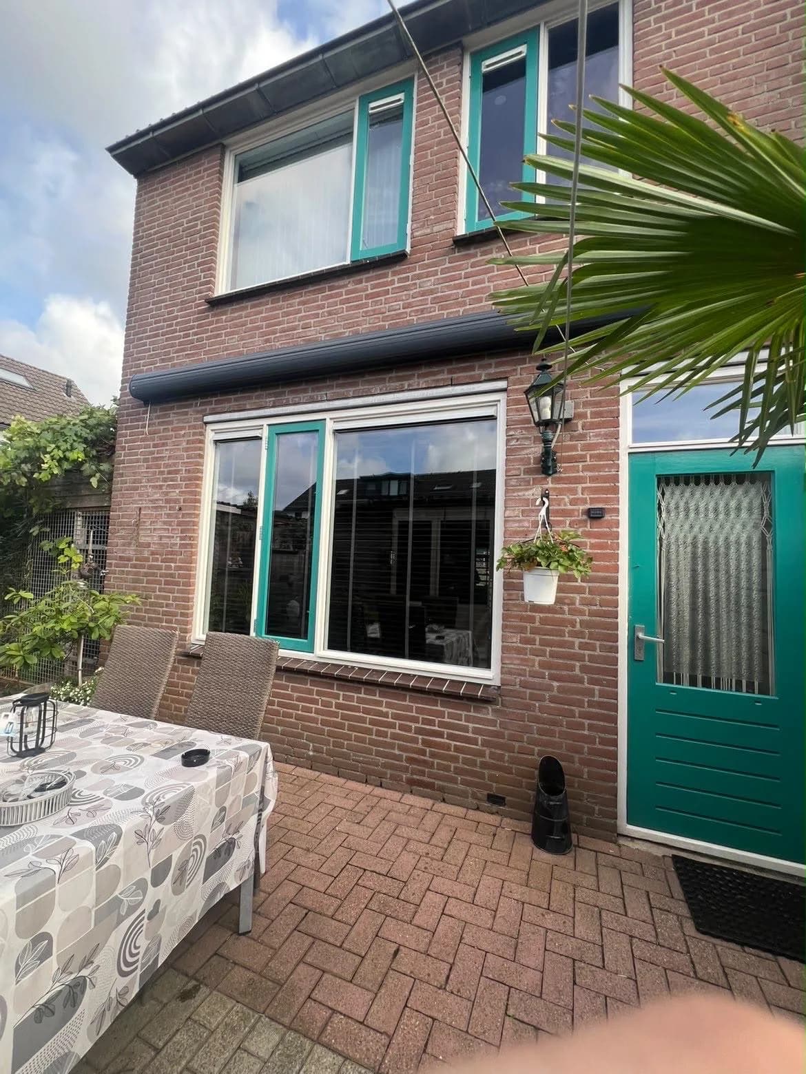 Achtergevel met schone ramen en kozijnen aan een terras