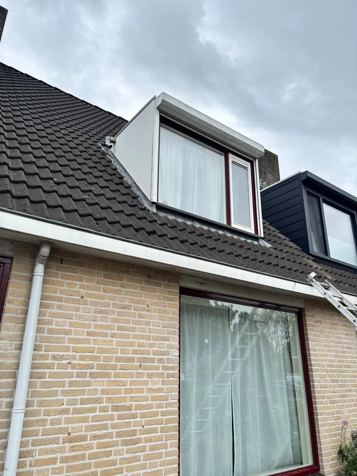Dakkapel op een rijwoning, ladder op de dakgoot