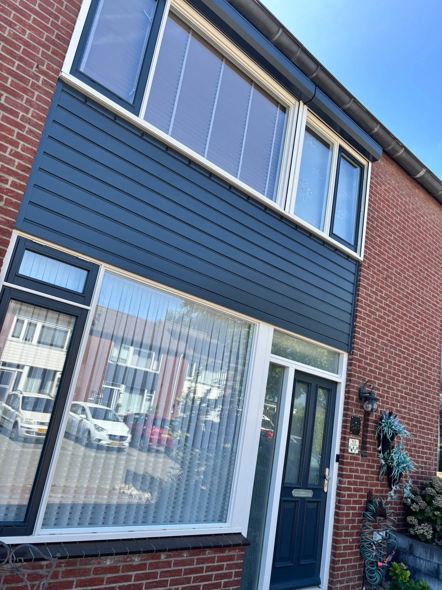 Rijwoning met donkerblauwe gevelplanken en grote ramen