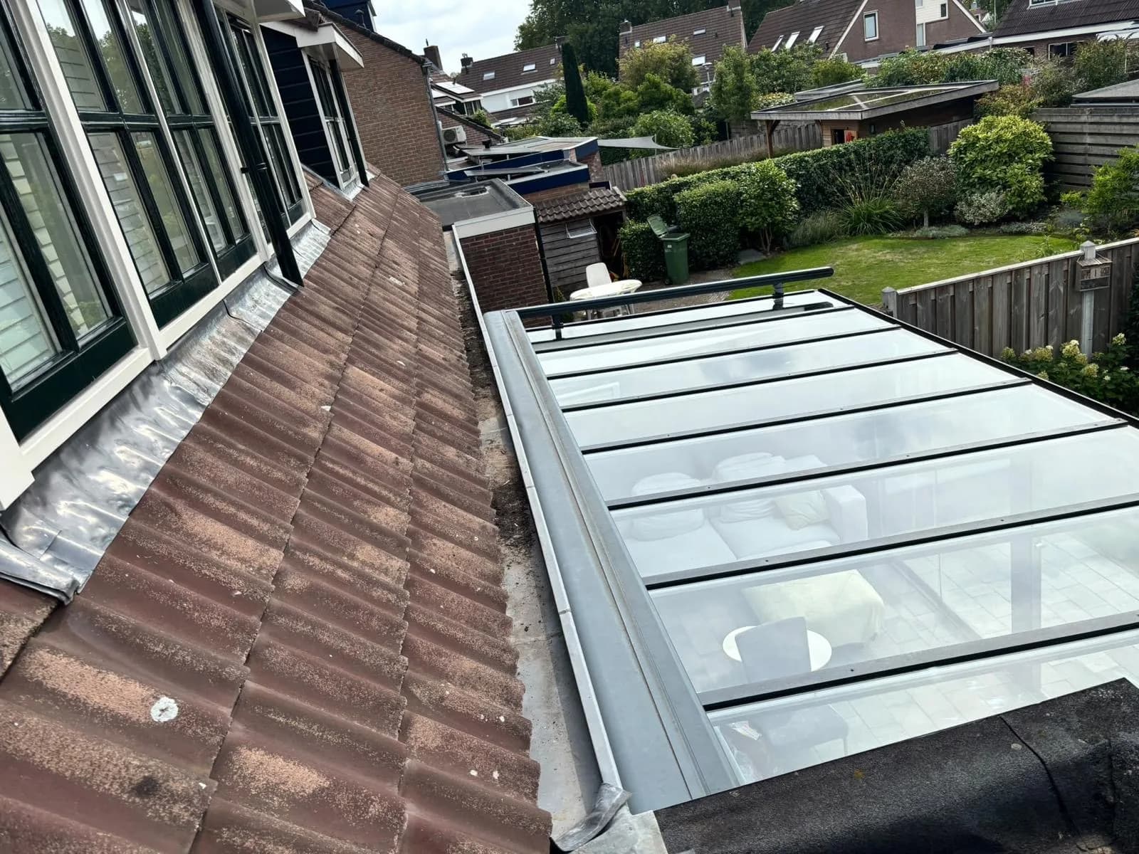 Glazen serredak naast een pannendak, van bovenaf